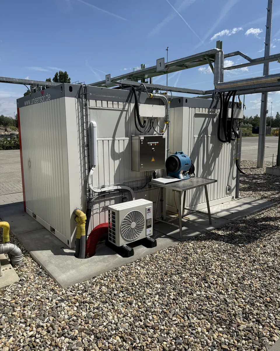 Door Duron geplaatste warmtepomp-buitenunit bij technische containers op een bedrijventerrein in Hengelo