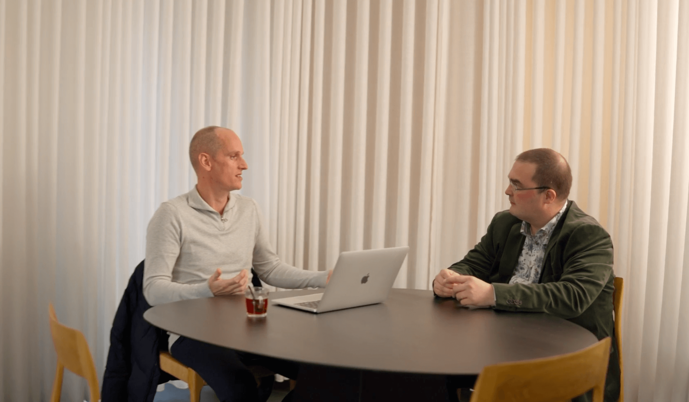 Twee mannen overleggen met een laptop aan een tafel op kantoor