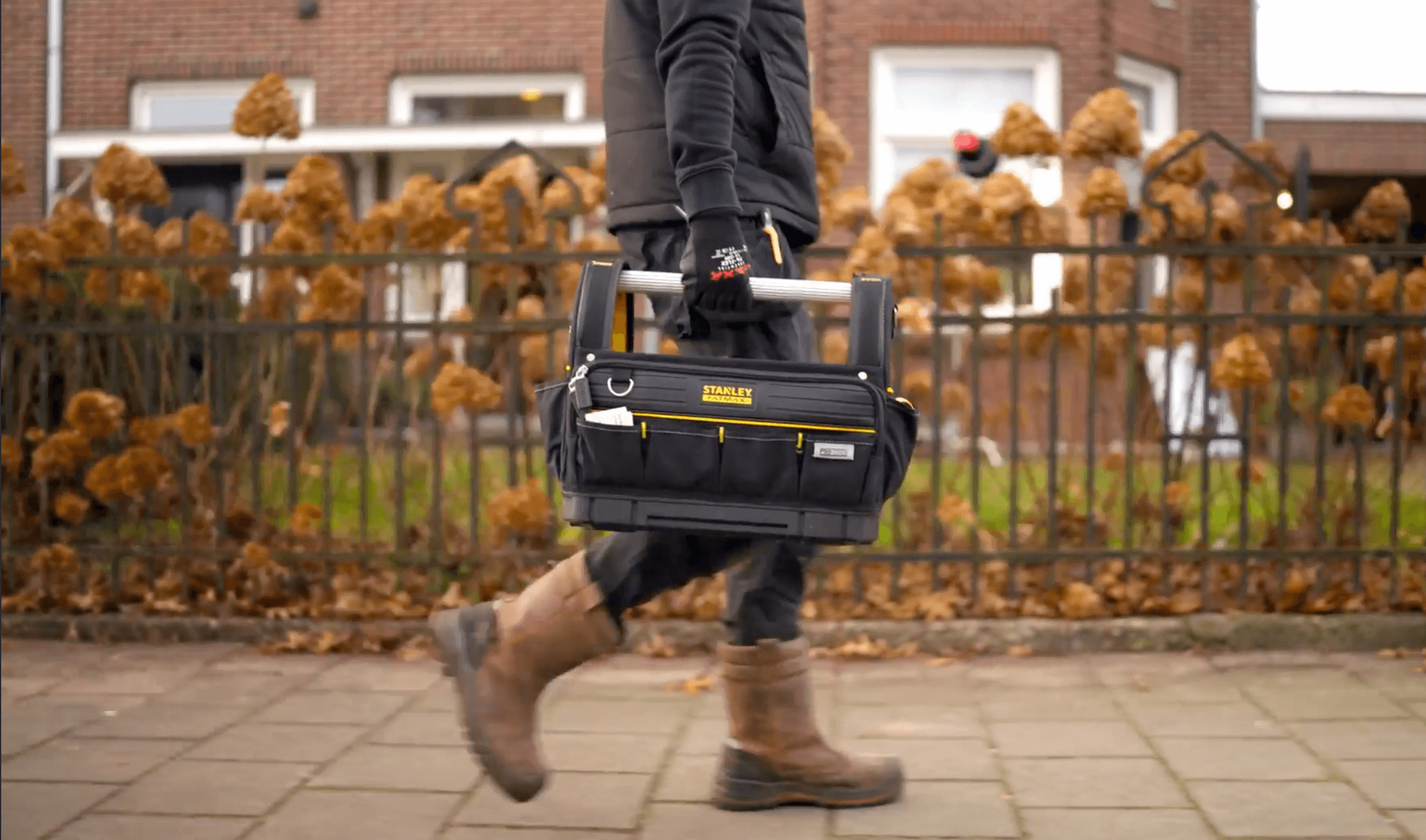 Monteur loopt met gereedschapskoffer naar een woning voor de schouw