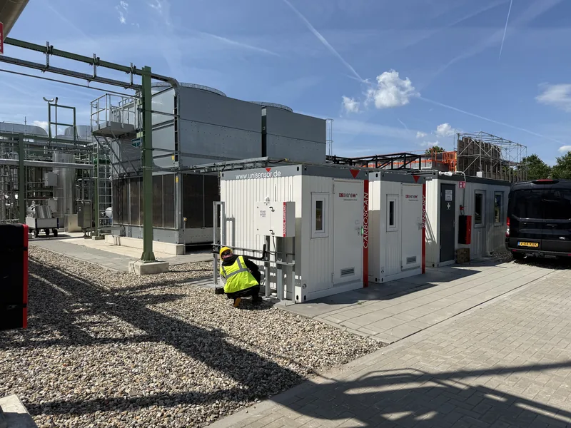 Monteur van Duron bij de technische containers met airco-buitenunits op het terrein van Twence in Hengelo